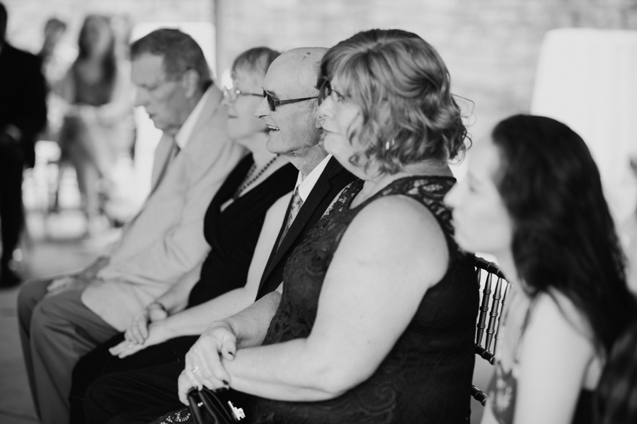 black and white of bride and groom's parents looking on during the ceremony