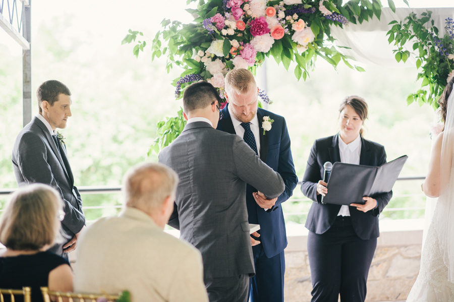 best man handing the wedding bands to the groom during the ceremony