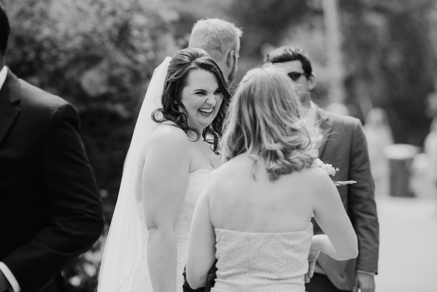 black and white of bride laughing with wedding guests