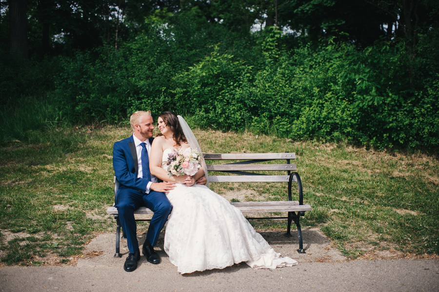 bride and groom sitting on a bench together at delaware park