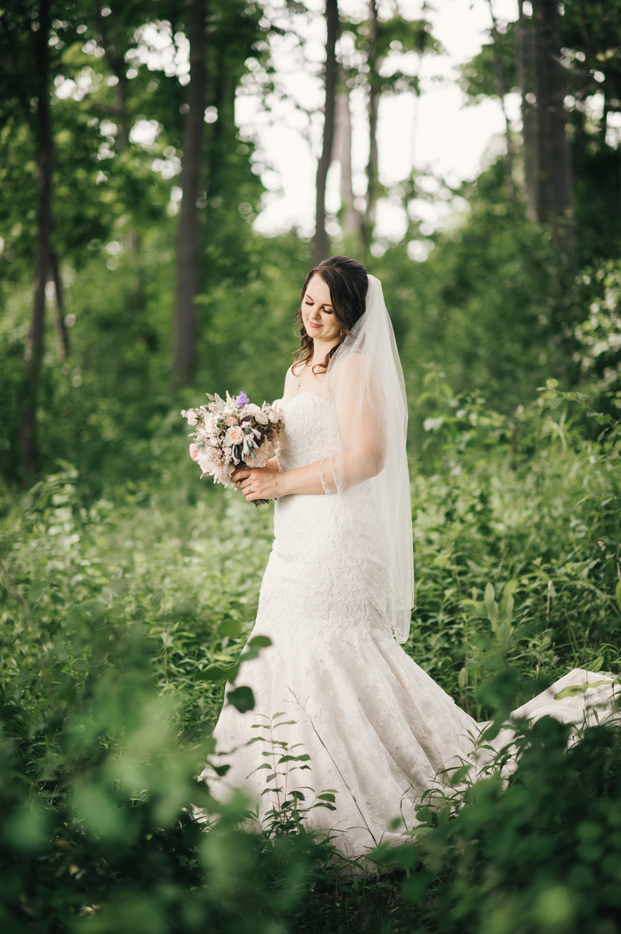 portrait of bride gazing at her bouquet by wild blossom hollow
