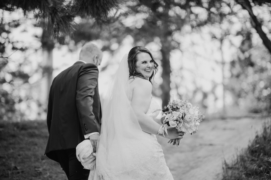 black and white of bride and groom walking up a path together