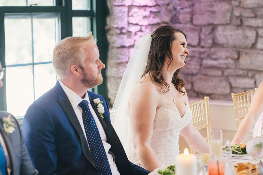 bride and groom smiling together during speeches