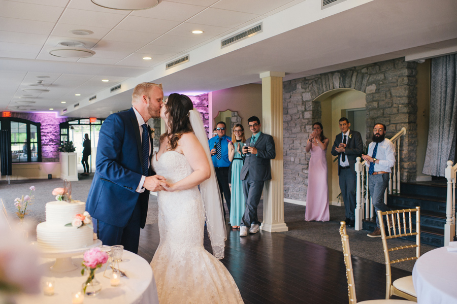 bride and groom kiss in front of wedding cake