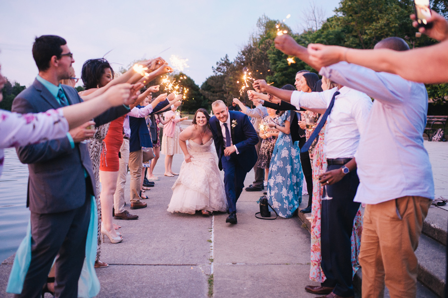 bride and groom running through sparklers at sunset next to hoyt lake