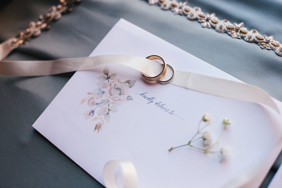 close up of wedding rings with bridal belt and RSVP card