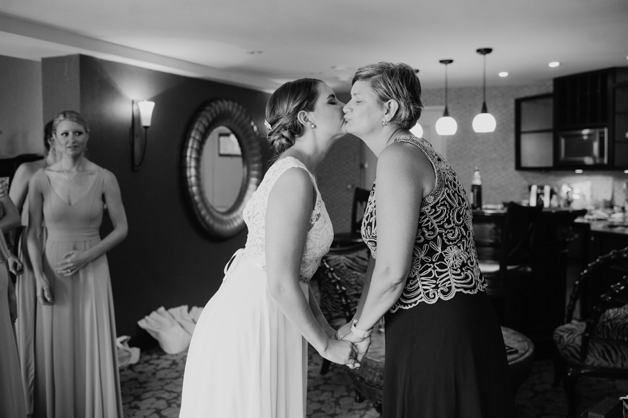 black and white of bride and her mother kissing each other on the cheek on wedding morning