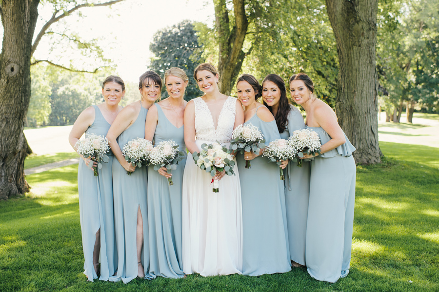 full length of bride with bridesmaids who are wearing long robins egg blue chiffon dresses and have bouquets of baby's breath and blush roses