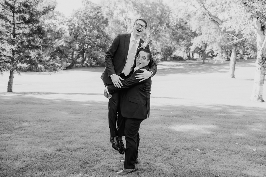 black and white of groomsman lifting up the groom around his legs