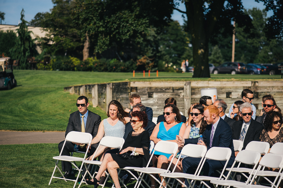 wedding guests sitting in ceremony chairs before the wedding begins