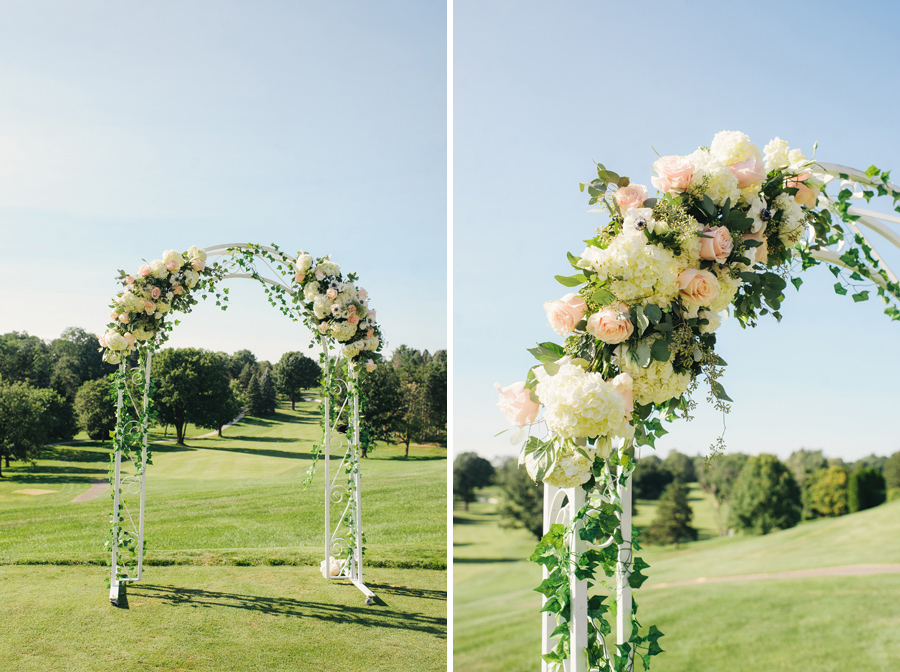 floral ceremony arch of white metal and white and blush pink flowers with greenery and vines