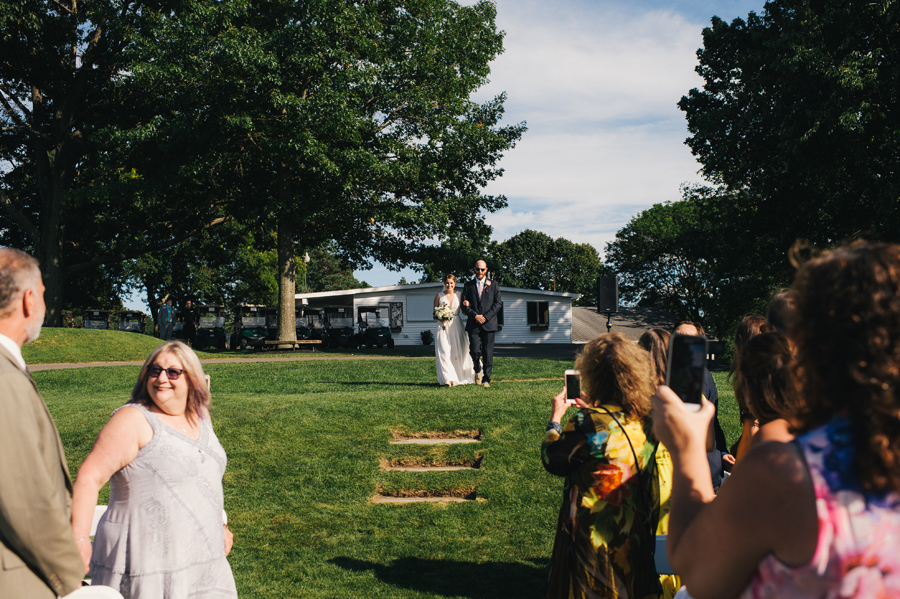 bride beginning to walk down the aisle outdoors with her brother