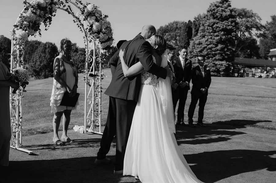 black and white of bride hugging her brother at the altar