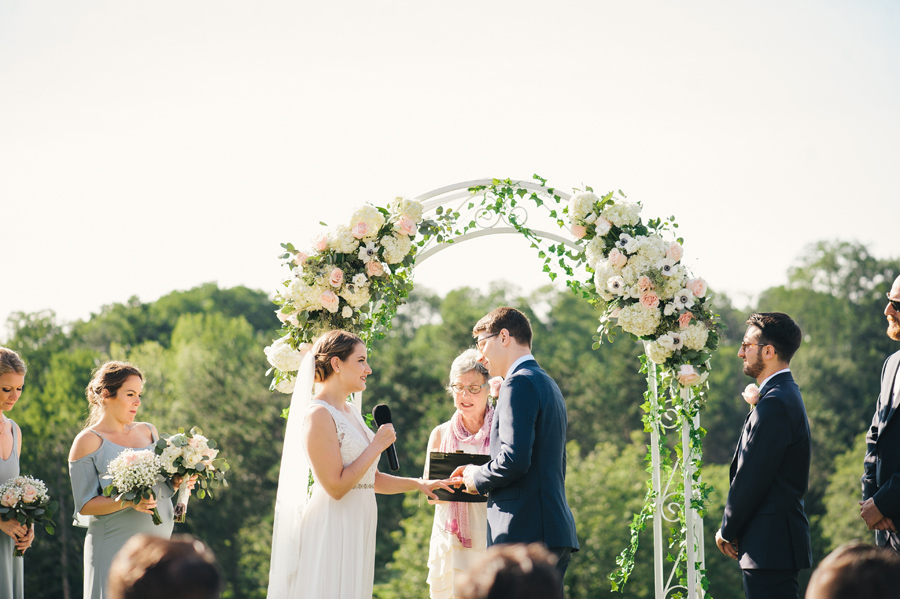 bride and groom saying vows during the ring exchange at their golf course wedding ceremony