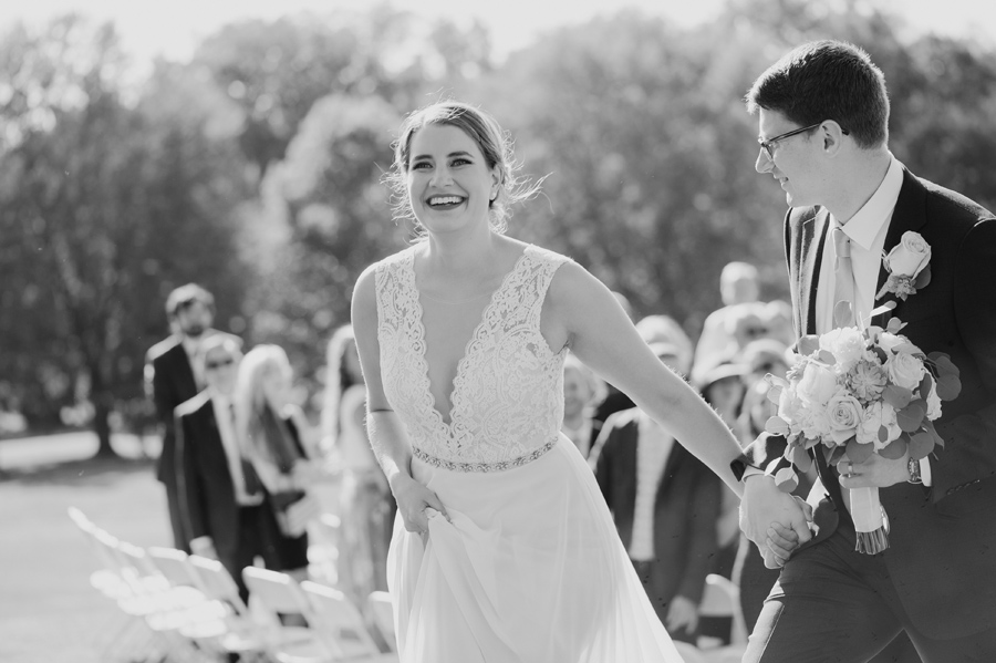 black and white of bride and groom walking back up the aisle after being married