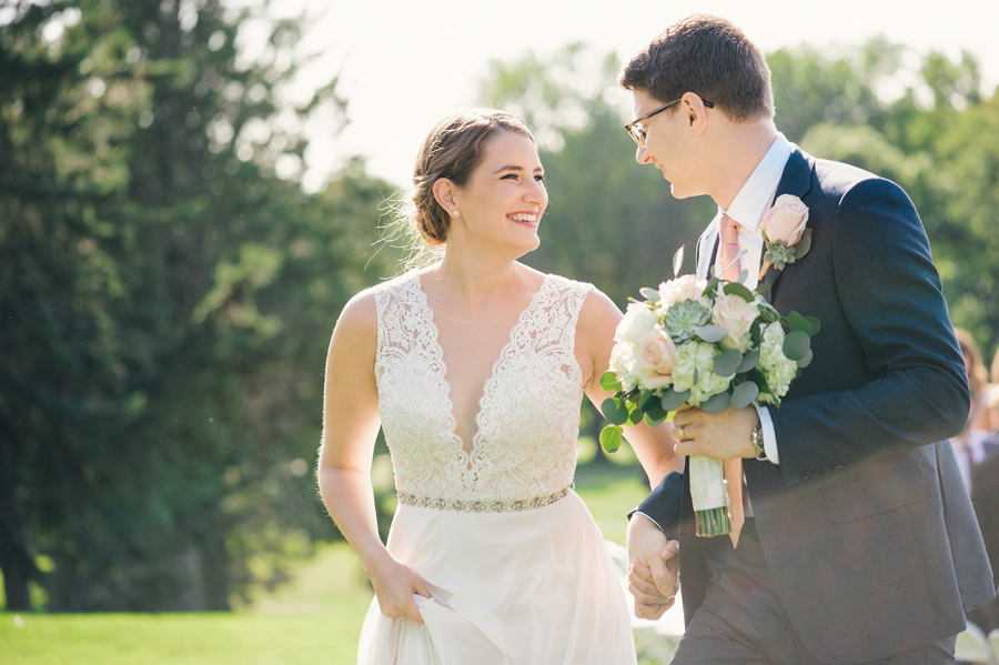 bride and groom smiling at each other after just exiting their ceremony