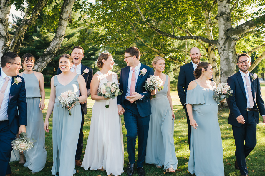 wedding party happily laughing and walking towards camera together