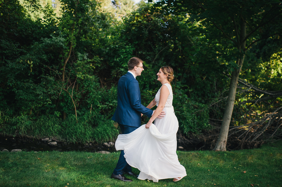 bride and groom dancing together outdoors near a small stream