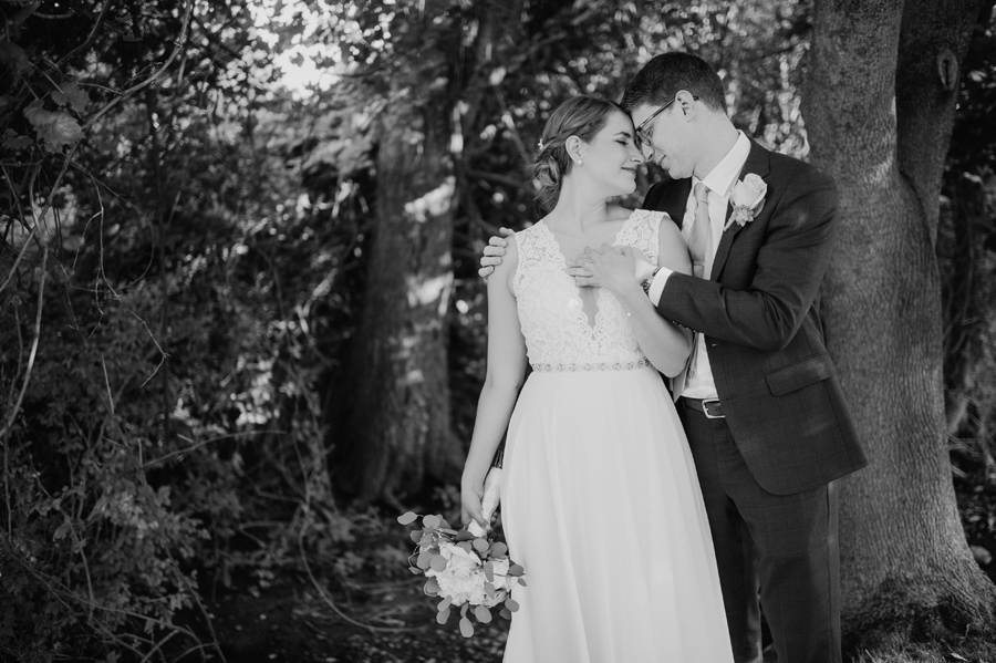 black and white of bride and groom touching foreheads with their eyes closed and embracing