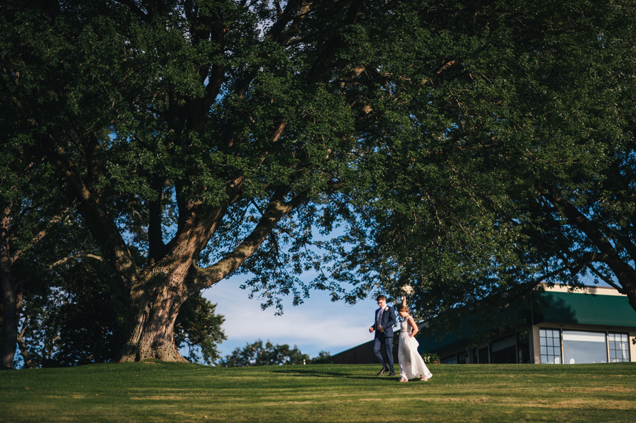 bride and groom running through the country club grounds together