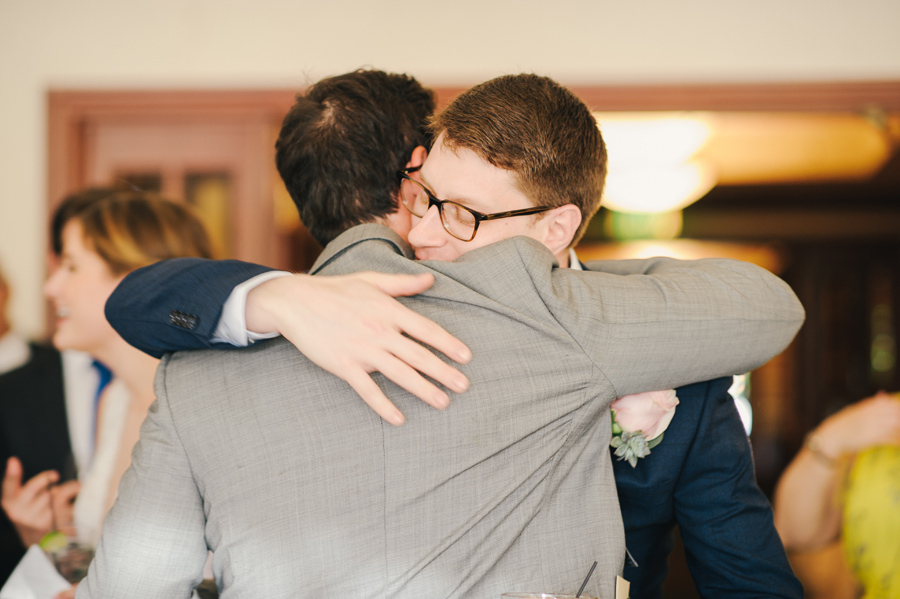 groom hugging a wedding guests as he enters the reception