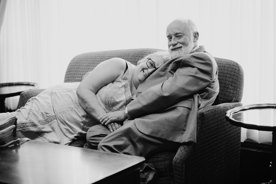 black and white of guests lounging on love seat at a wedding reception