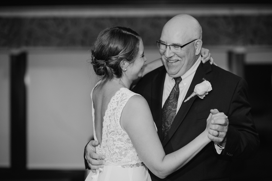 black and white of bride and her father smiling during the father daughter dance