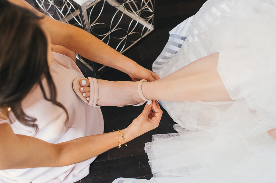 a bridesmaid helping the bride with her shoes