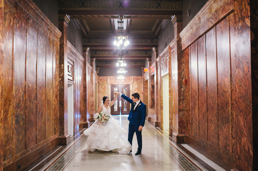 groom twirling his bride around in their hotel's hallway