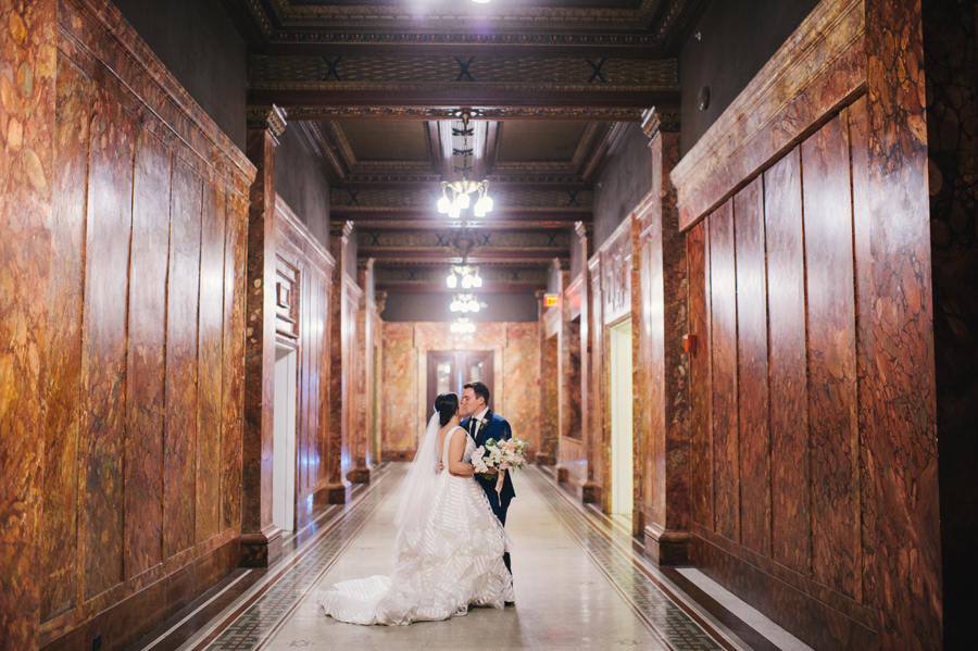 bride and groom kissing in the hallways of their wedding venue