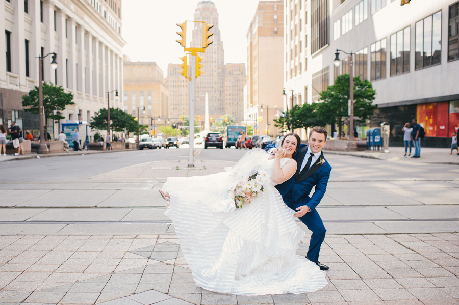 bride leaning into the groom with her leg in the air in the middle of a city street