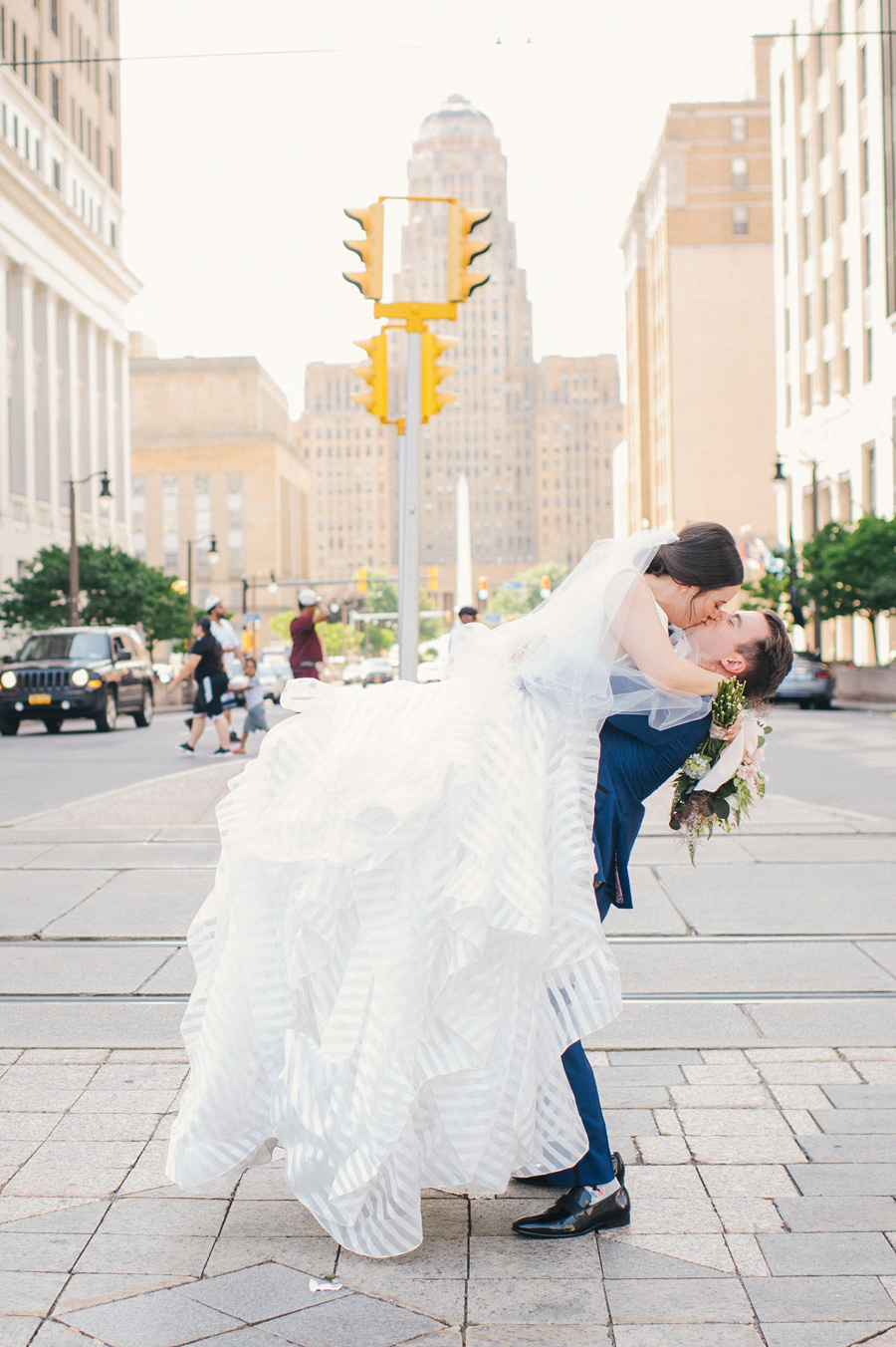 groom lifting and kissing bride under a traffic light