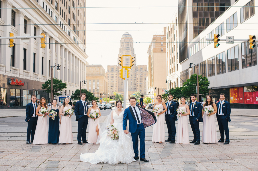 groom showing off his custom made suit with wedding party on a city street