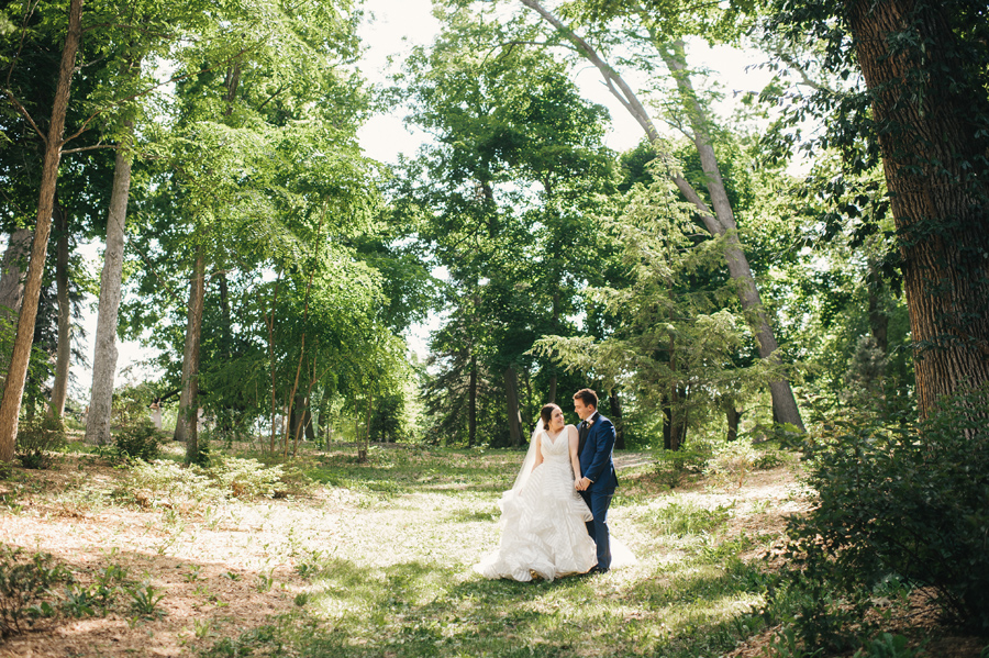 bride leaning into groom and smiling in a wooded area