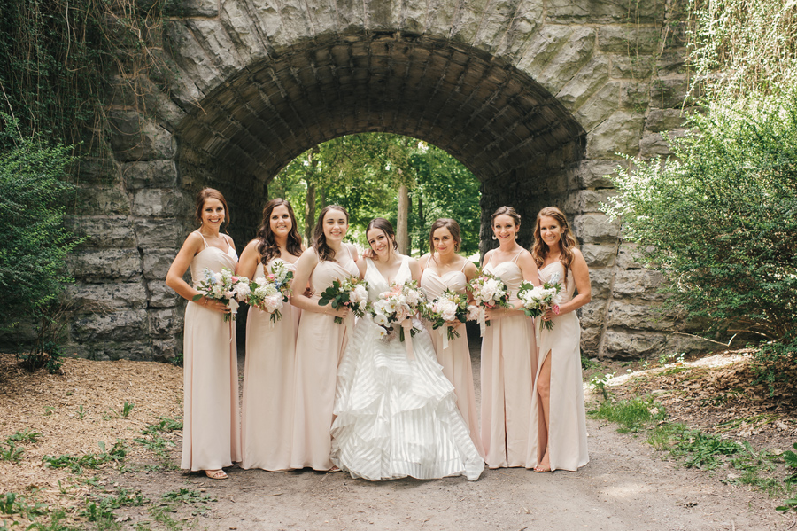 full length of bride and bridesmaids smiling for the camera