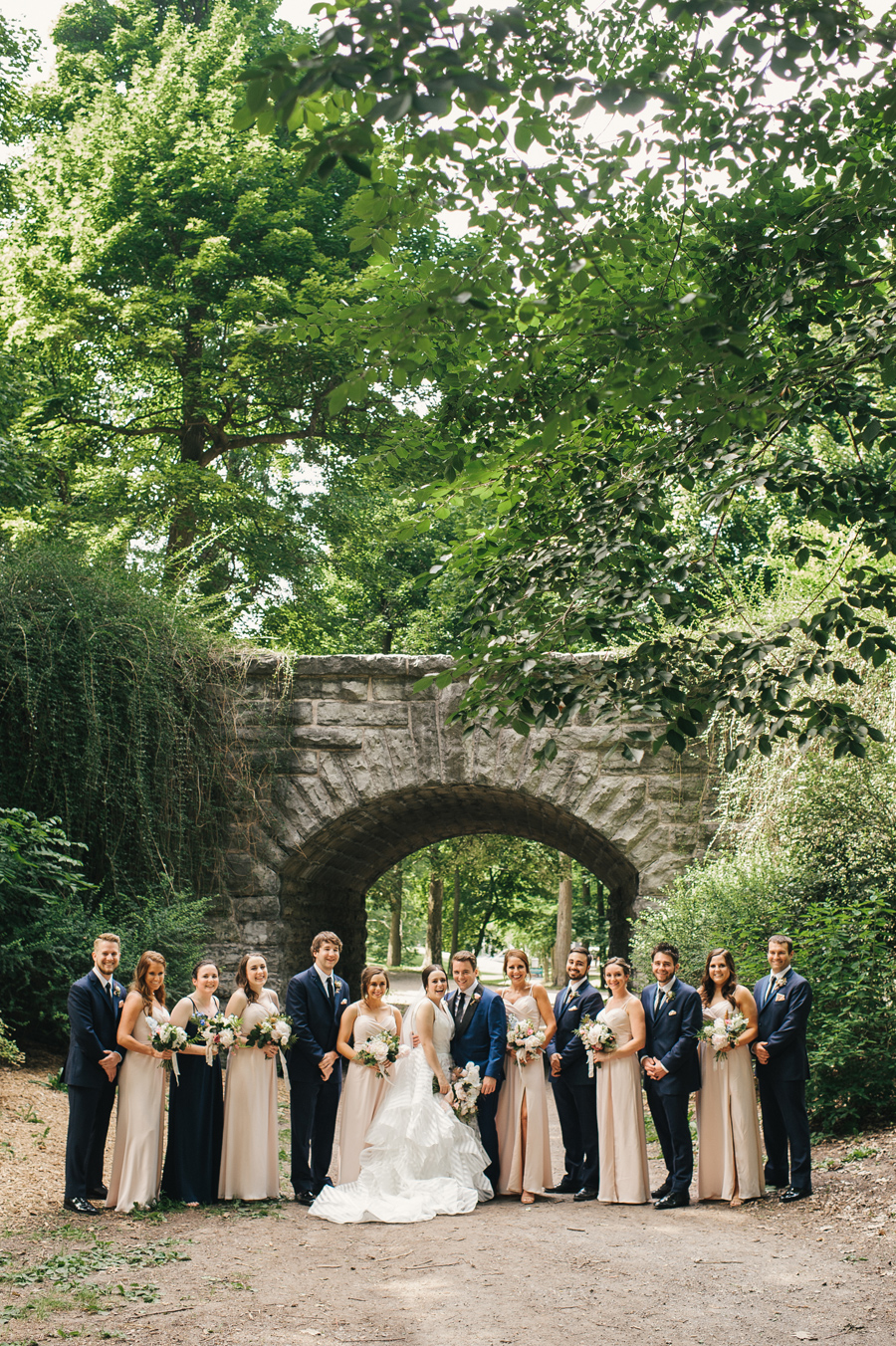 entire wedding party smiling for the camera in the park