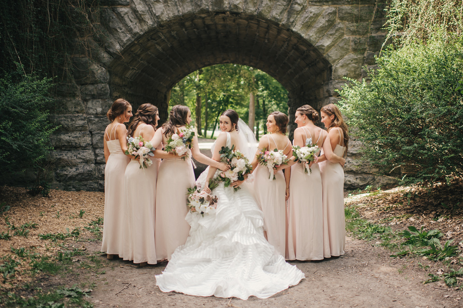 bridal party facing away from camera while bride looks back at camera over her shoulder and smiles