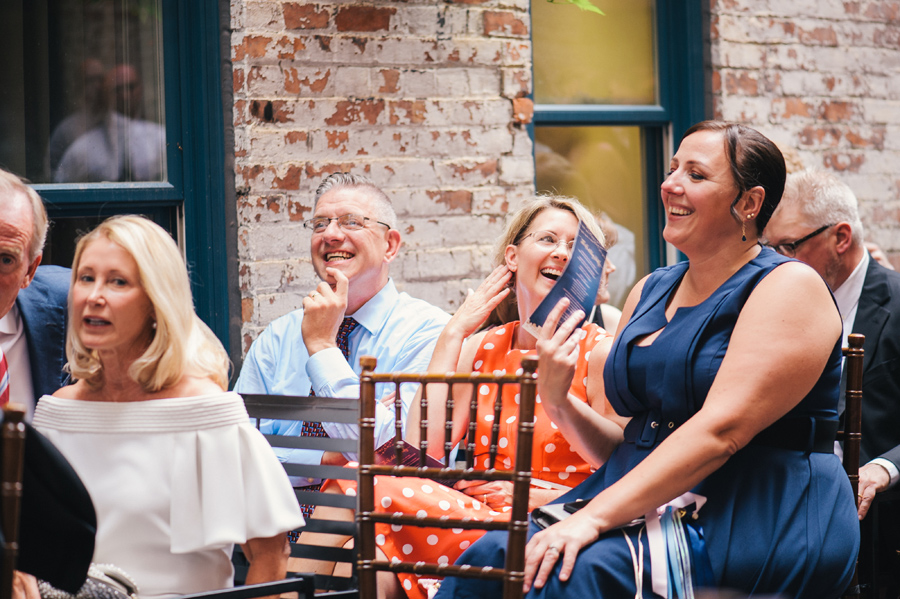 guests smiling and fanning themselves in the ceremony space