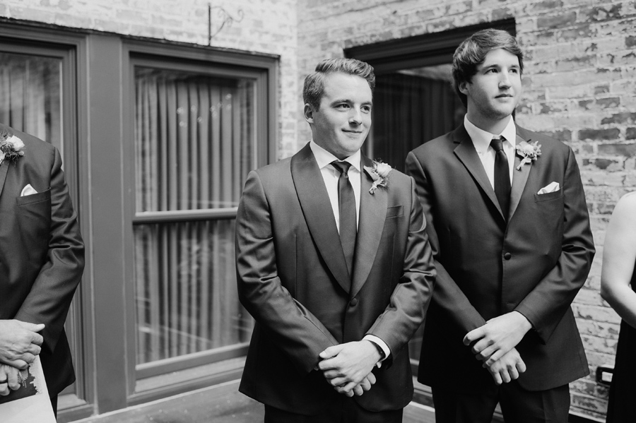 black and white of groom waiting for his bride at the altar