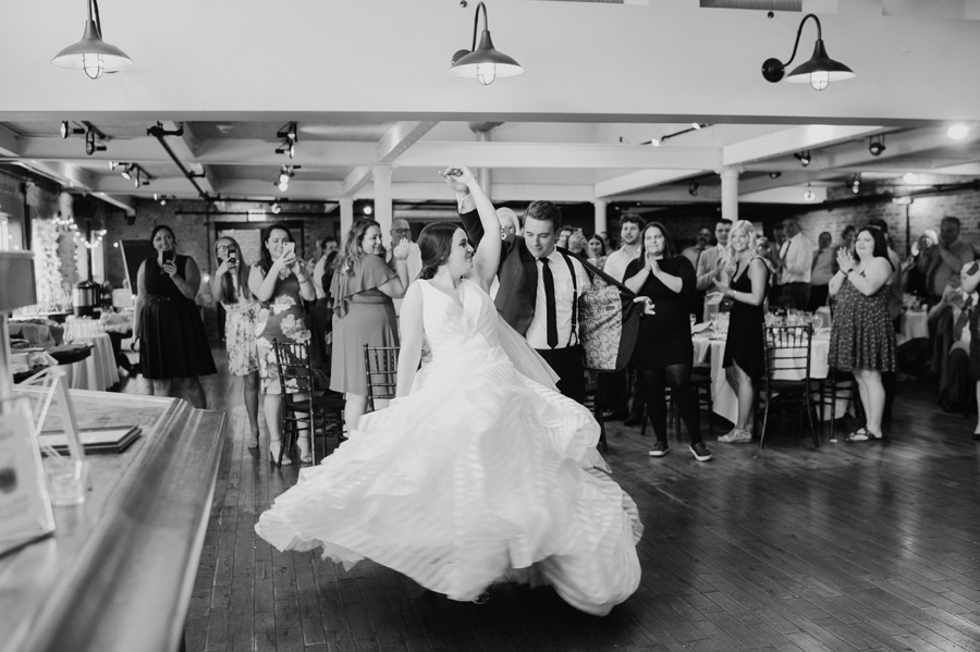 black and white of groom spinning the bride while they make their grand reception entrance