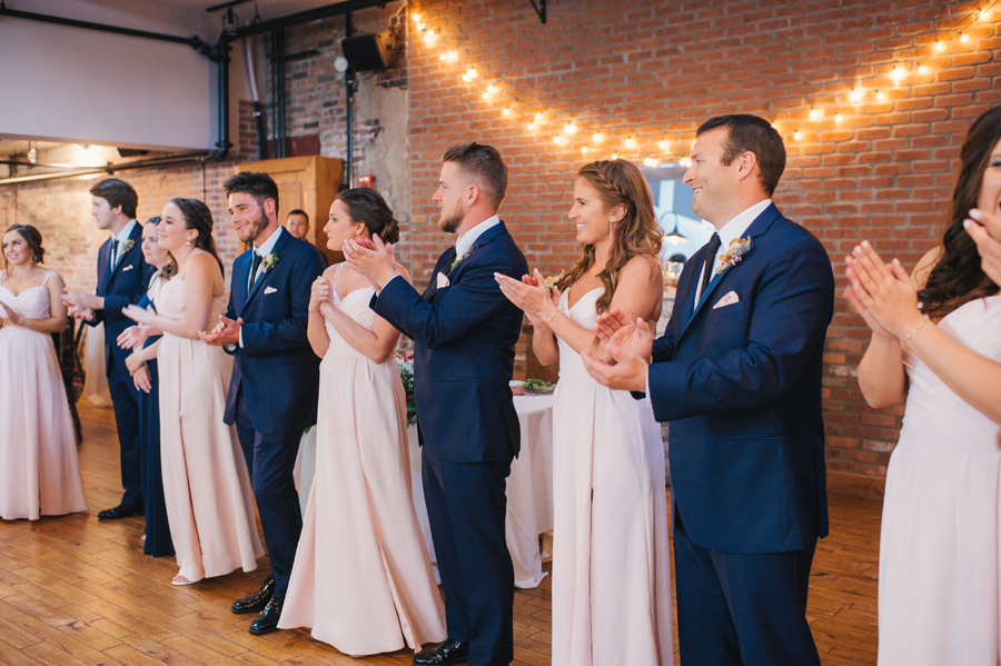 wedding party clapping and welcoming the bride and groom to their reception