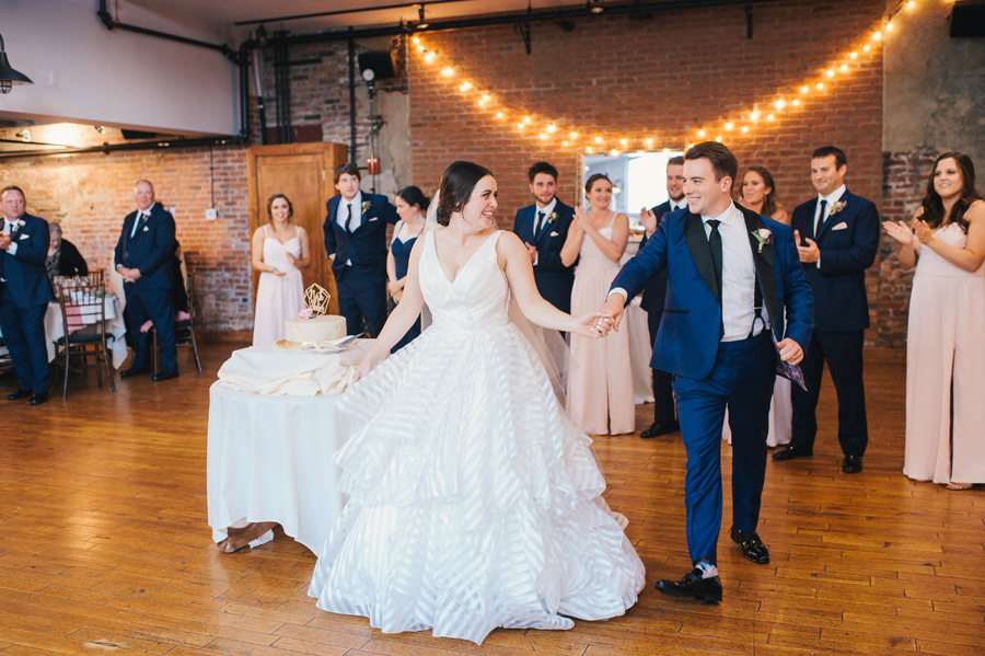 bride and groom holding hands and smiling during their reception entrance