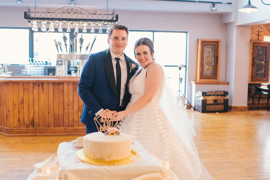 bride and groom smiling for the camera before they cut their cake