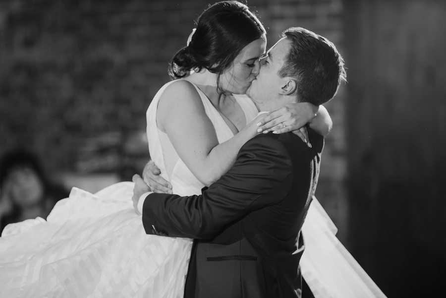 black and white of the groom lifting and kissing the bride during their first dance