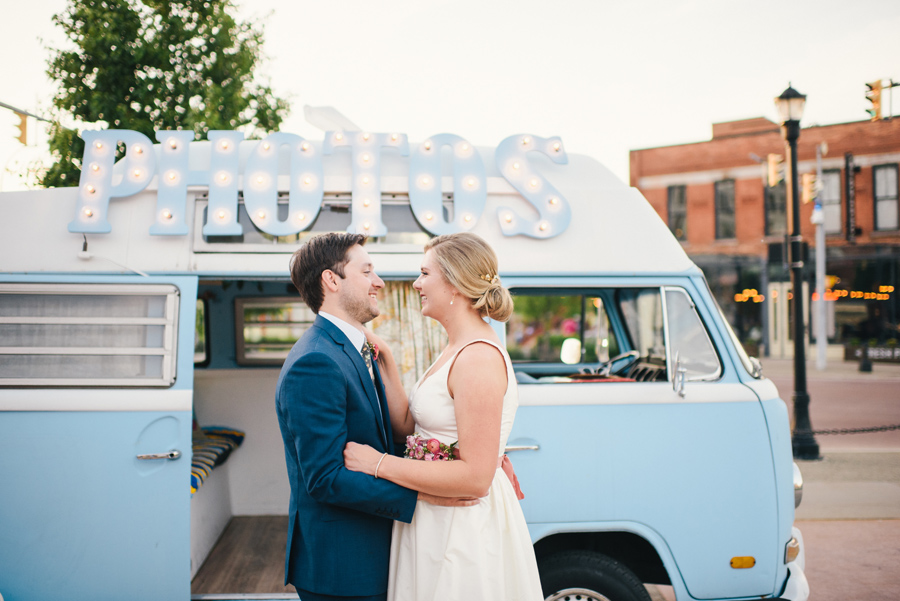 bride and groom smiling at each other in front of photo booth bus