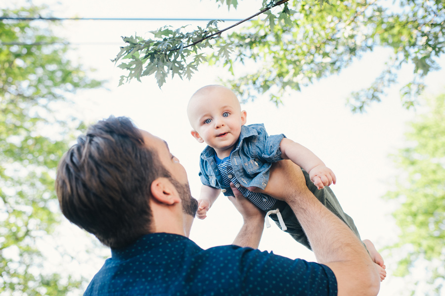 father lifting baby who is looking at camera