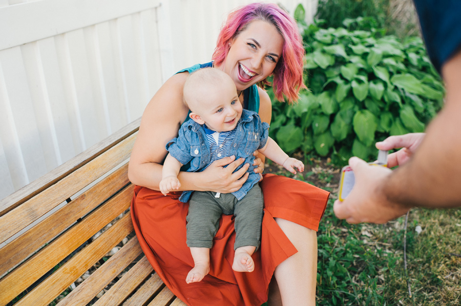 mom sitting on bench laughing with baby sitting in her lap