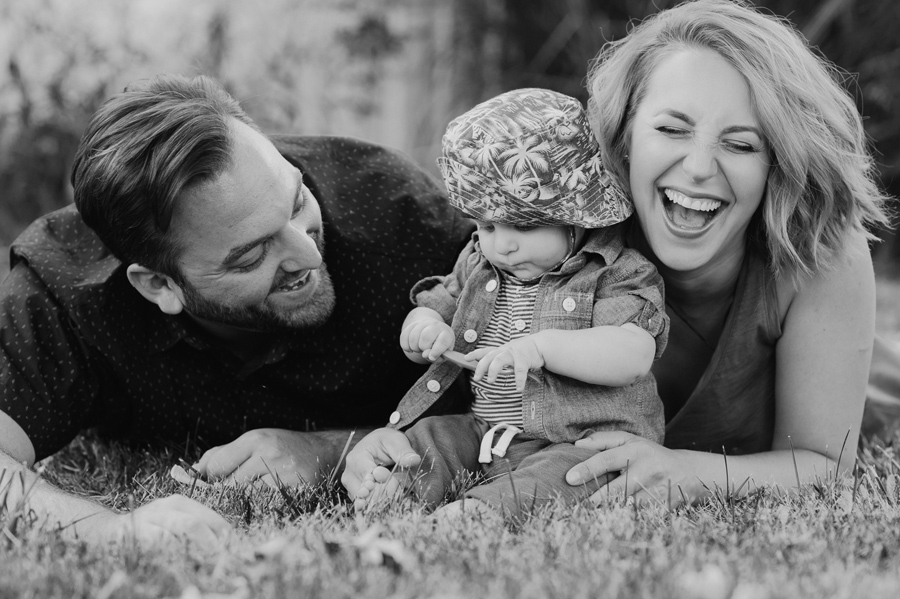 black and white close shot of family laying on stomachs in the grass laughing