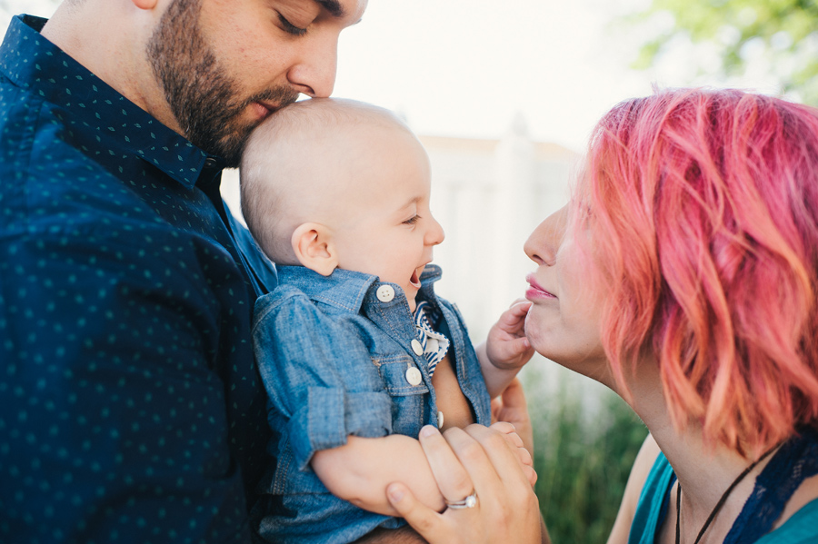 dad holding baby while mom makes him laugh