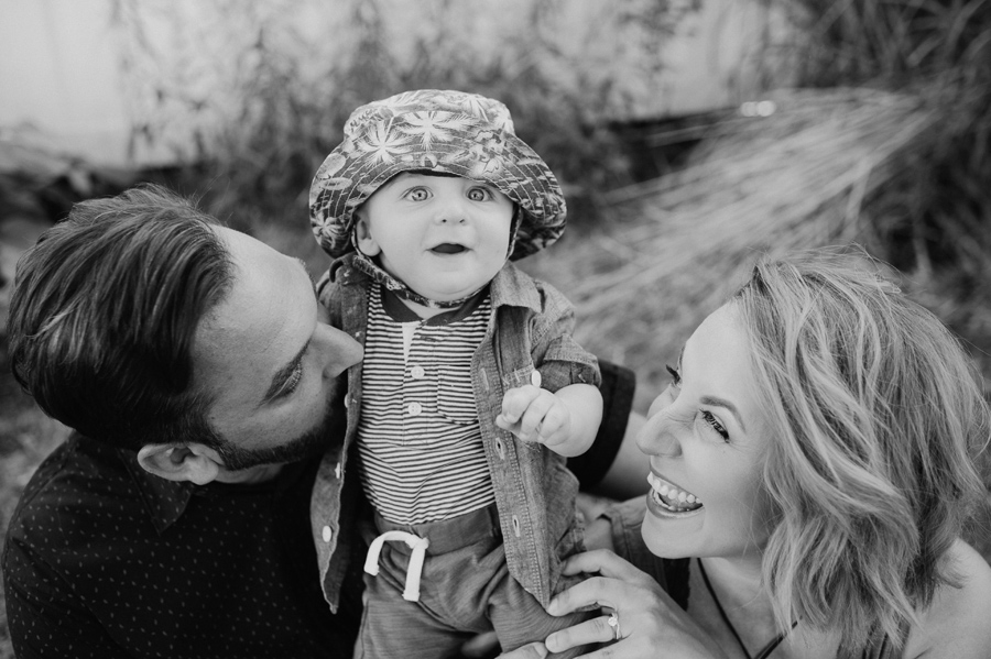 black and white close up of baby boy looking amazed and mom and dad laughing